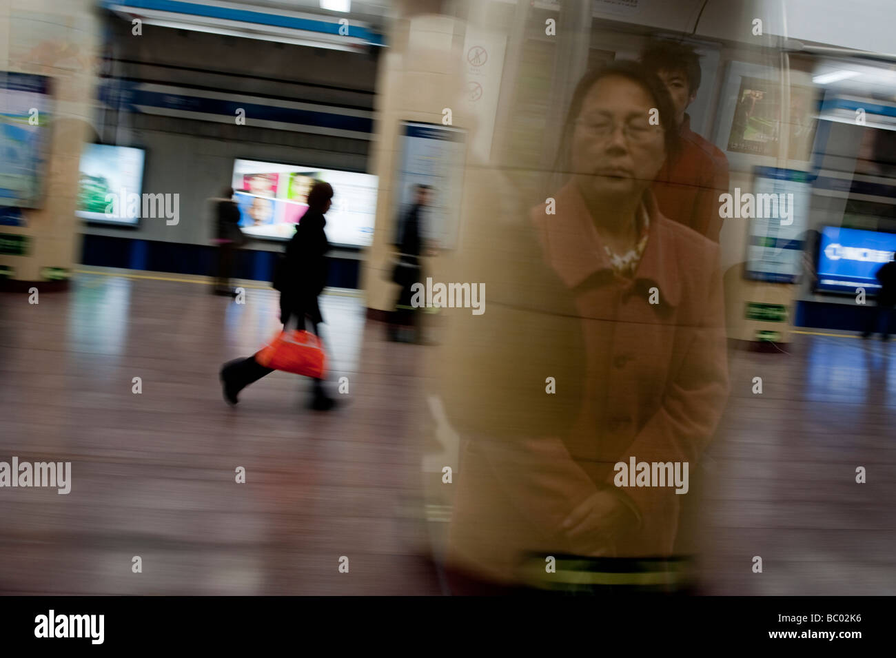 Una signora avente un momento di solitudine in una stazione della metropolitana che arrivano in corrispondenza di una stazione a Pechino, Cina. Foto Stock
