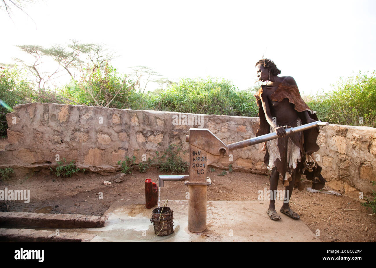 Una donna più anziana pompe acqua da un pozzo nel rurale Hamer villaggio del sud Etiopia. Foto Stock