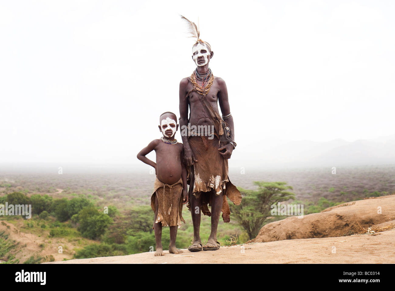 Una nonna si erge con suo nipote vestito in abiti tradizionali che si affaccia sulla valle dell'Omo nel sud Etiopia. Foto Stock