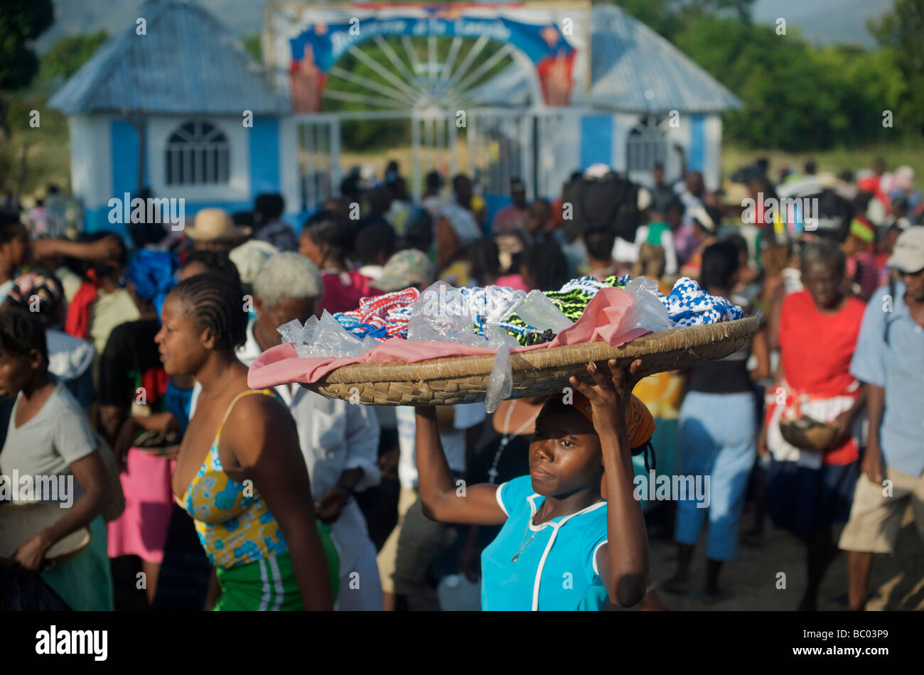 Una donna vende collane di una folla di persone che frequentano un festival voodoo in Haiti. Foto Stock