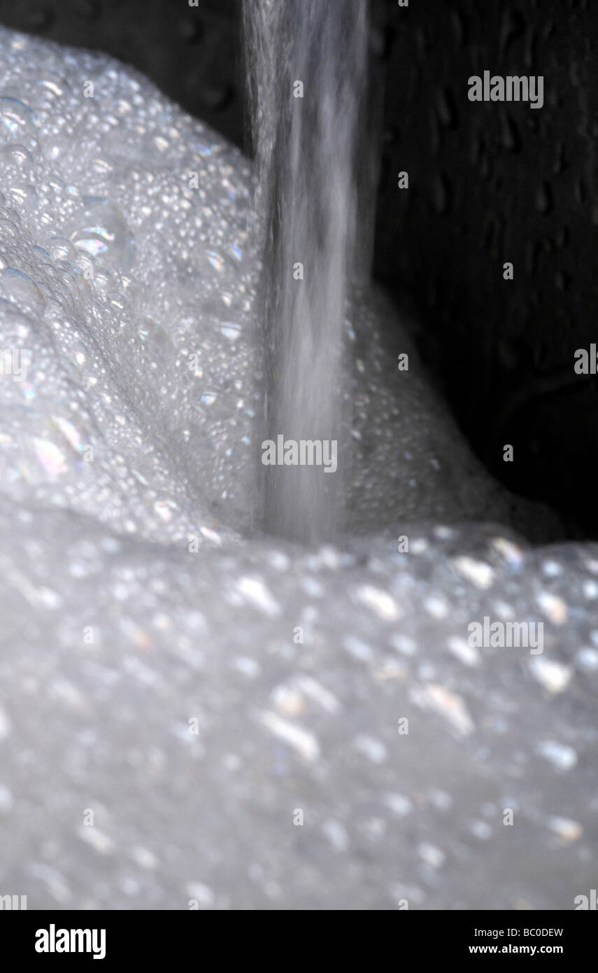 L'acqua scorre in un lavandino di schiuma di sapone. Foto Stock