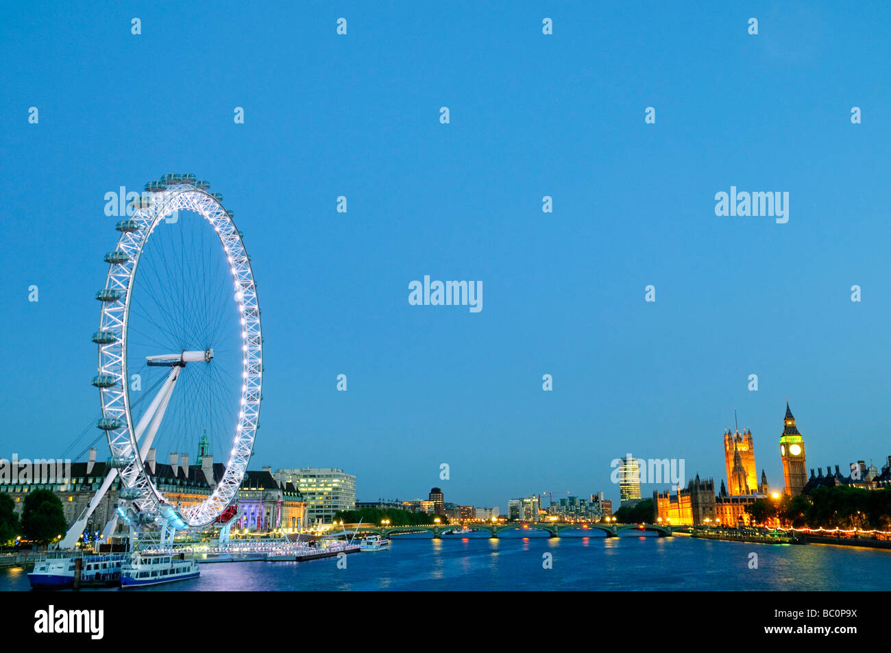 Londra, UK - London Eye (sinistra) torri sopra il Tamigi all'imbrunire, con il Palazzo di Westminster (Casa del Parlamento e dal Big Ben) a destra. Alta risoluzione panorama. Foto Stock
