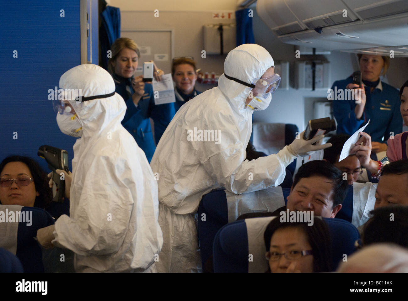 Lavoratori medici a bordo di un aereo da Amsterdam controllare i passeggeri per i segni di febbre (influenza suina) dopo lo sbarco a Shanghai Foto Stock