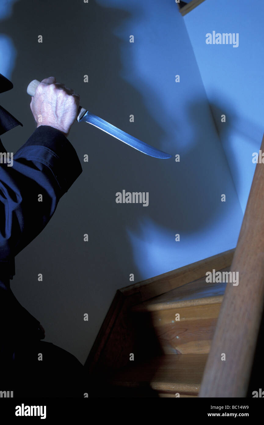 Uomo con coltello e ombra sulle scale in una scena criminale, USA Foto Stock