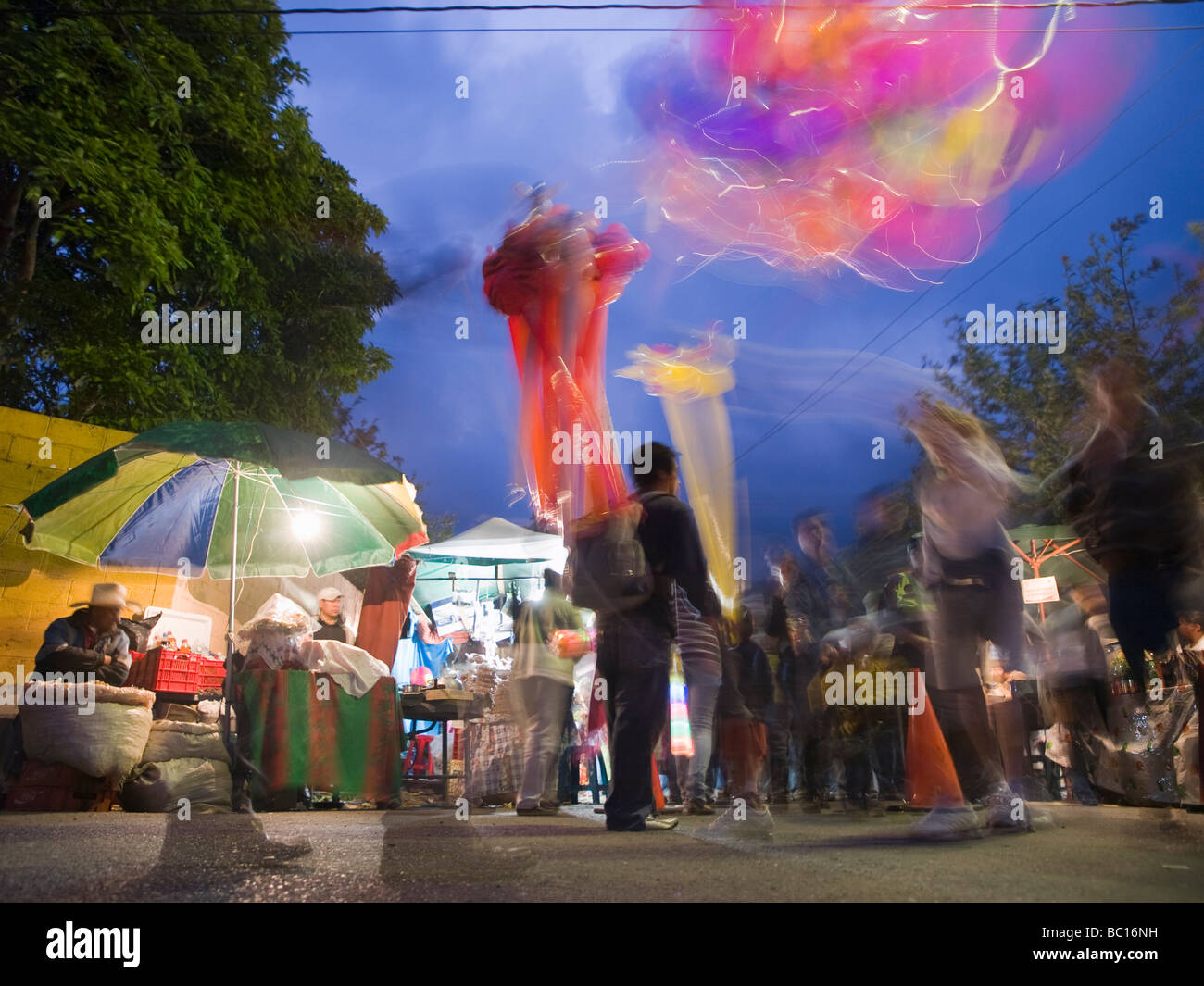 Durante un festival di strada, un uomo vende palloncini al crepuscolo. Foto Stock