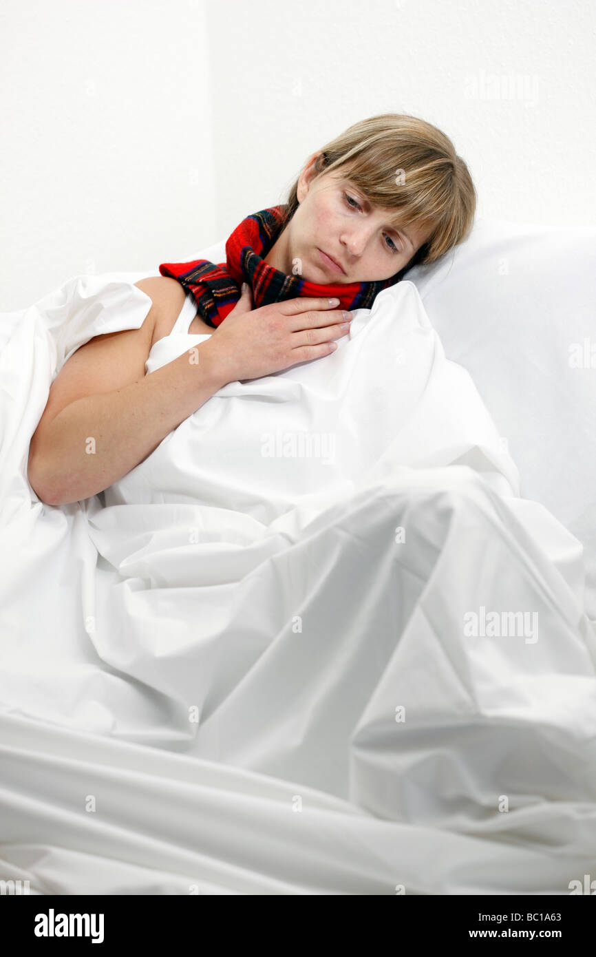 Donna con una sciarpa in letto ha un raffreddore mal di gola Foto Stock