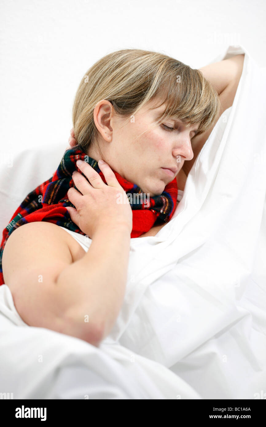 Donna con una sciarpa in letto ha un raffreddore mal di gola Foto Stock