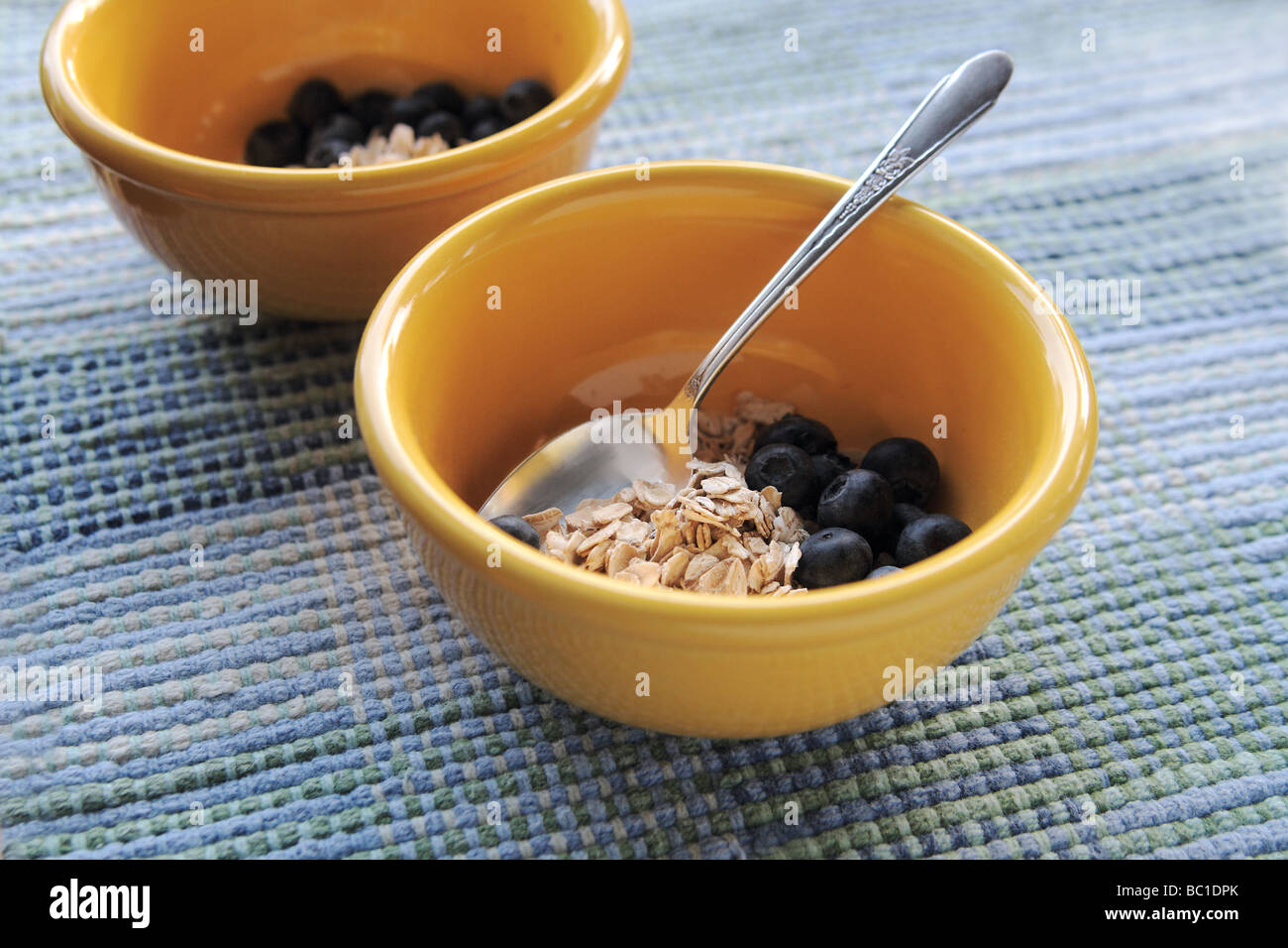 Non cotti i fiocchi d'avena con mirtilli freschi di colore giallo luminoso bocce Foto Stock