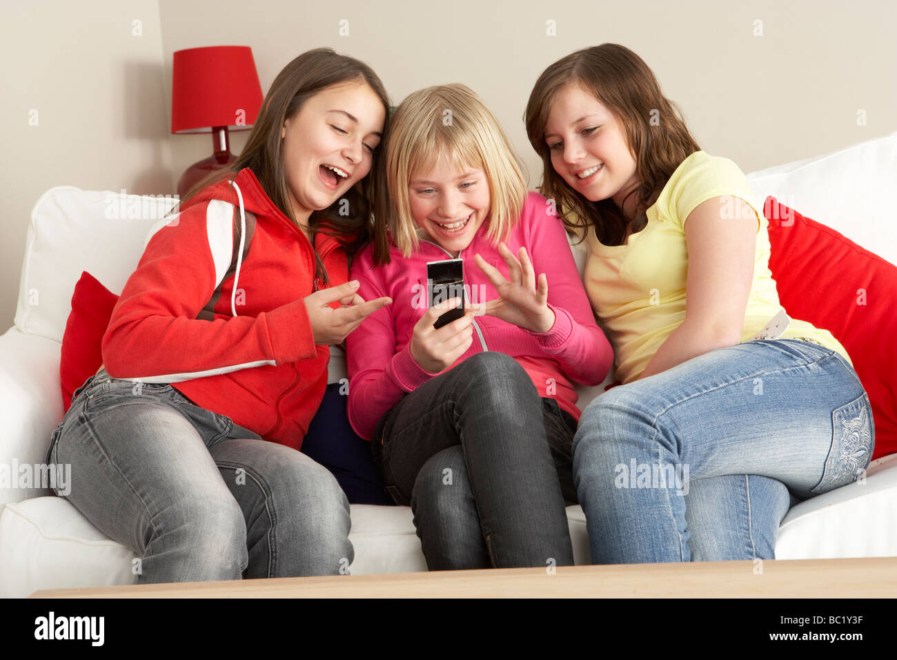 Un gruppo di tre ragazze di lettura dei messaggi di testo Foto Stock