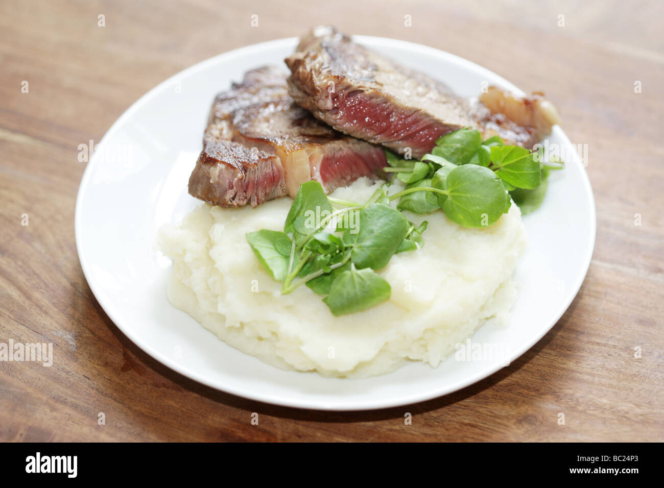 Cucinato al momento raro lombata di carne di manzo con purea di patate e crescione servita su una piastra con n. di persone Foto Stock