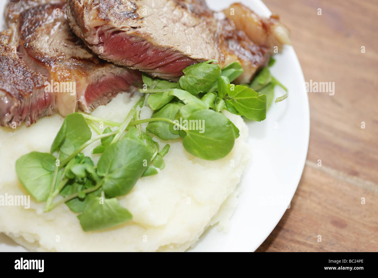 Cucinato al momento raro lombata di carne di manzo con purea di patate e crescione servita su una piastra con n. di persone Foto Stock