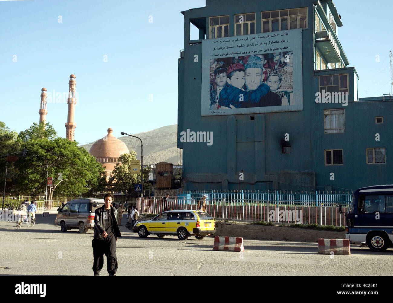 Afghanistan il presidente Hamid Karzai, circondata da piccoli bambini, guarda al di fuori di un poster sbiaditi in una strada nel centro di Kabul Foto Stock