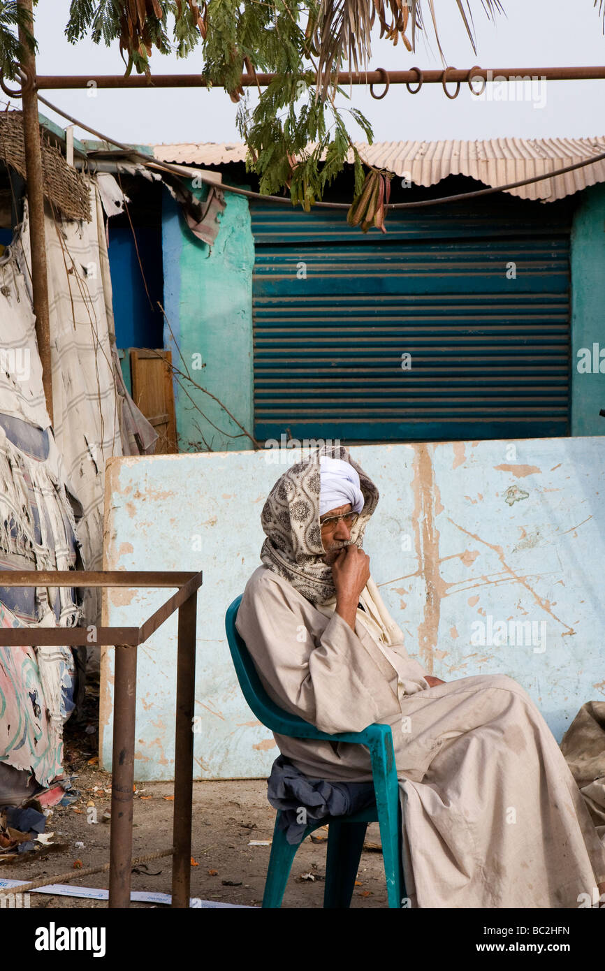 Colore verticale shot egiziano di uomo seduto sulla sedia in plastica al di fuori del negozio chiuso a Luxor, Egitto Foto Stock