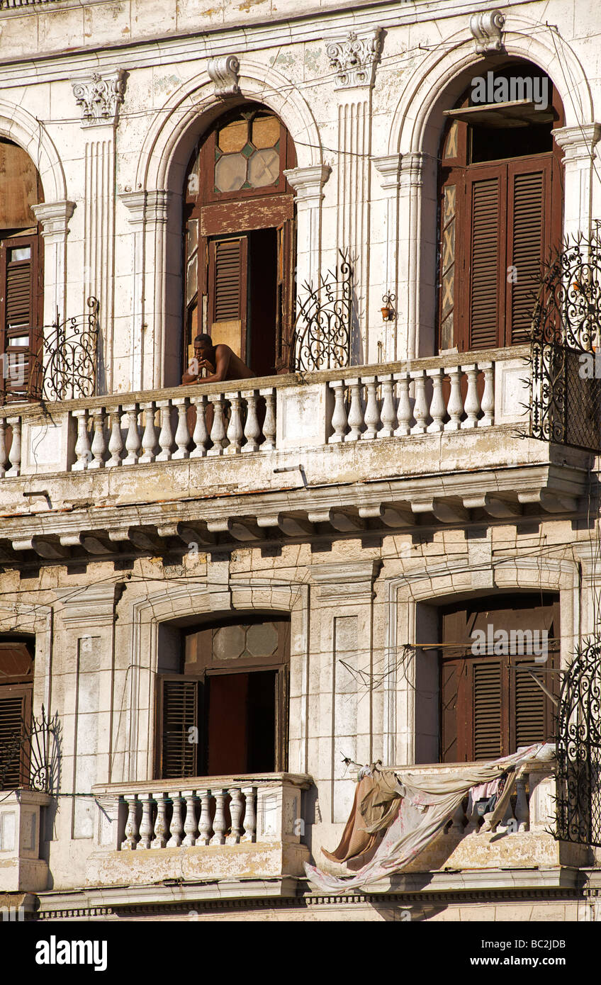 Uomo al balcone per la sua camera. Facciata di un edificio in stile coloniale, ora in multi occupancy. Central Plaza, Havana. Cuba Foto Stock