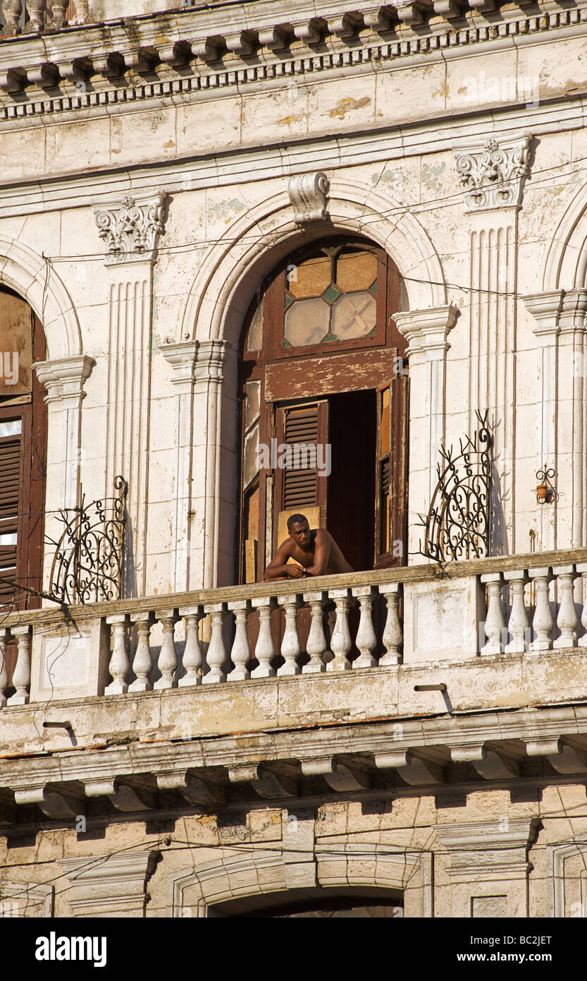 Uomo al balcone della sua camera. Facciata di un edificio in stile coloniale, ora in multi occupancy. Central Plaza, Havana. Cuba Foto Stock