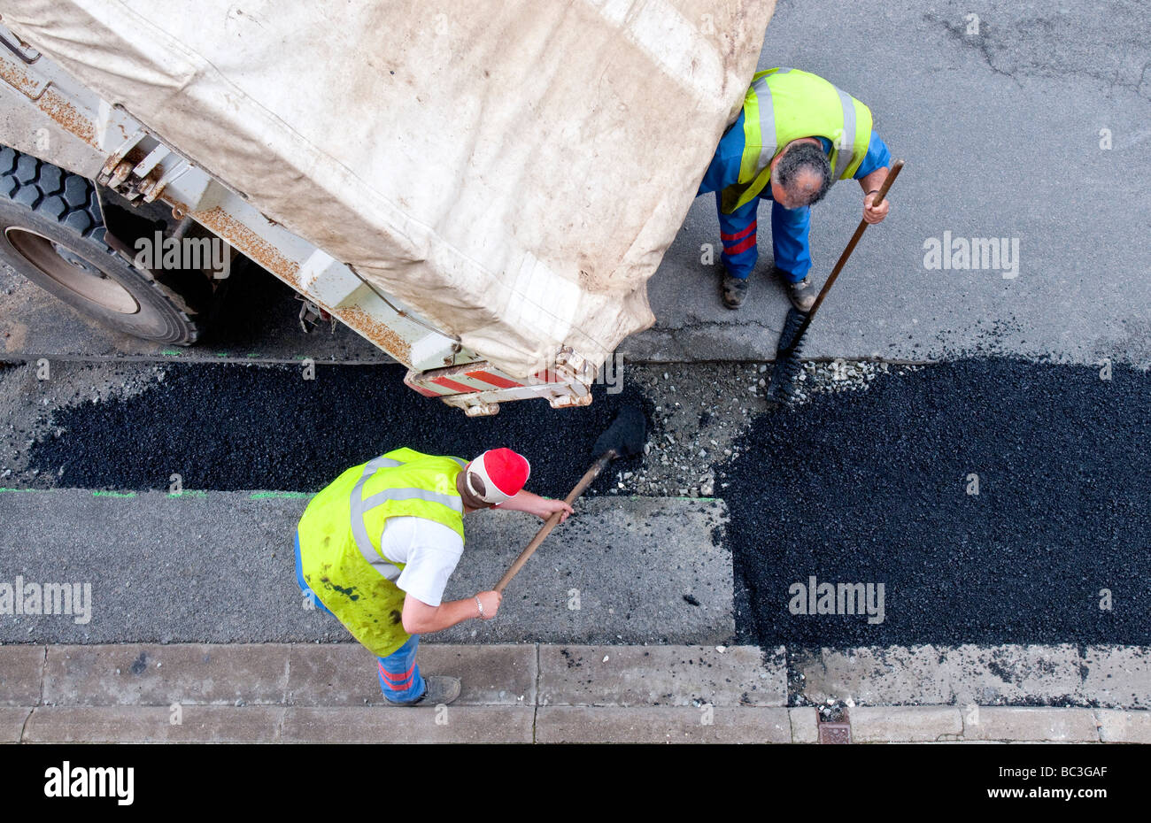 Lavori stradali appaltatori diffusione di tarmac versata da autocarro ribaltabile - Francia. Foto Stock