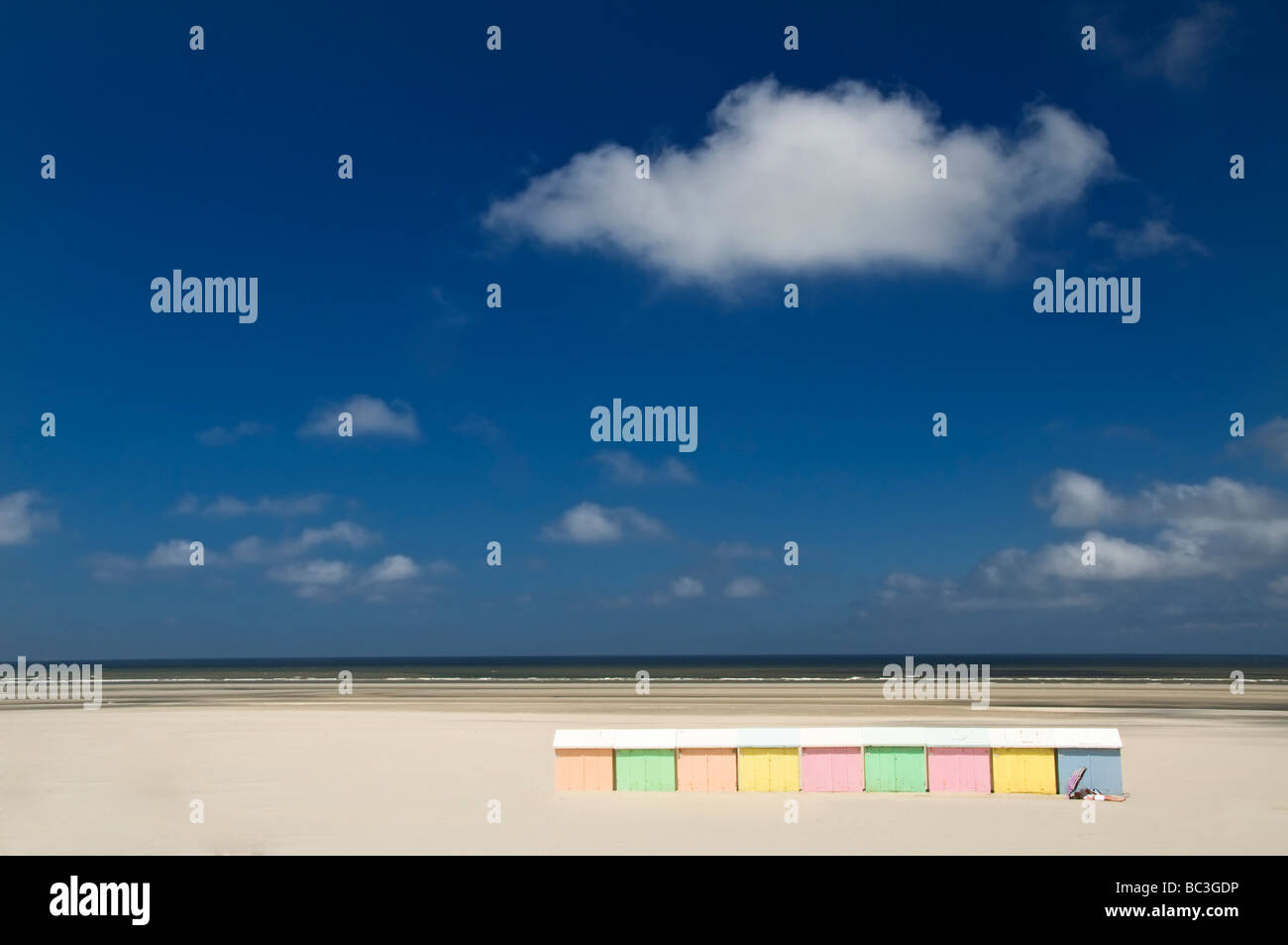 Cabine sulla spiaggia, Francia color pastello cabine sulla spiaggia, ombrellone e prendere il sole sulla coppia pura deserta spiaggia di sabbia bianca Berck sur Mer Francia settentrionale Foto Stock