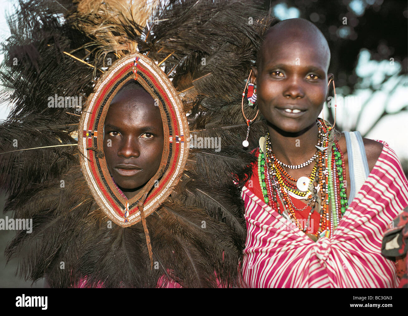 Uomo masai tradizionale di piume di struzzo copricapo donna sposata cordone collane orecchini Riserva Nazionale di Masai Mara Kenya Africa Foto Stock
