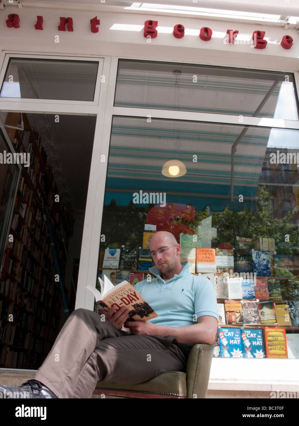 Uomo di lettura al di fuori del libro di seconda mano bookshop chiamato Saint Georges nella bohemian Prenzlauer Berg di Berlino Foto Stock