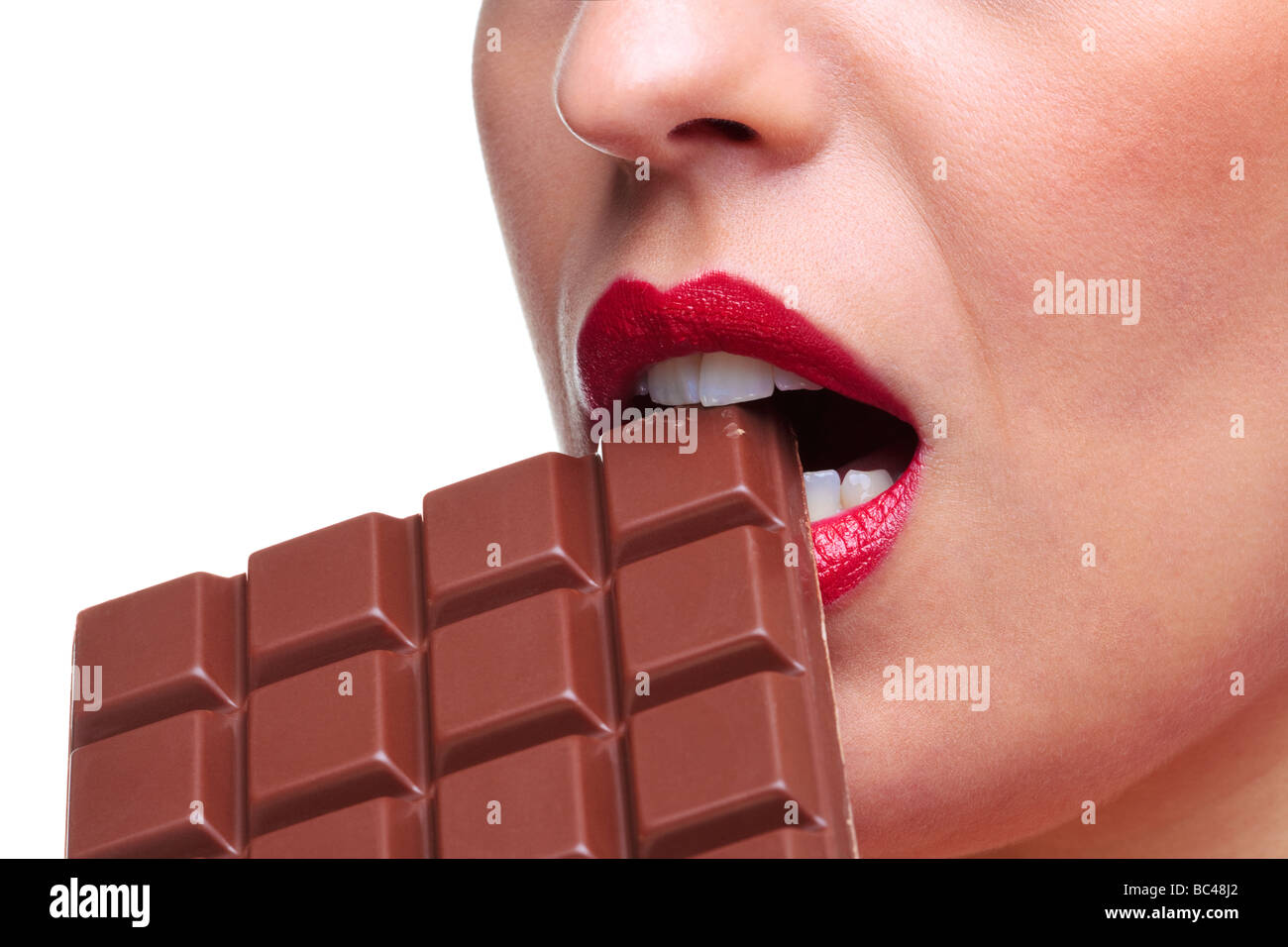 In prossimità di una donna con rossetto rosso a mangiare una barretta di cioccolato di sfondo bianco Foto Stock