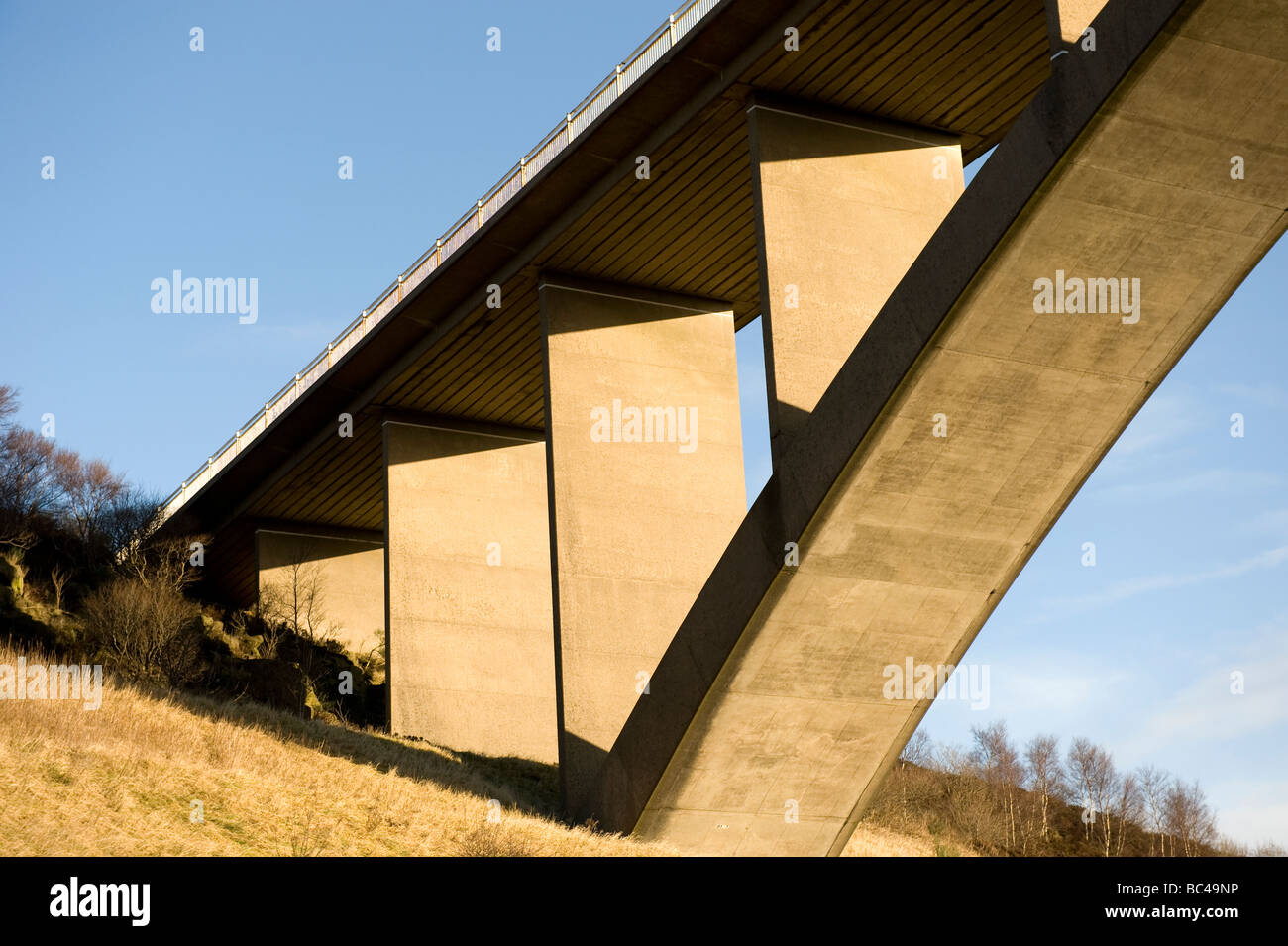 Ponte autostradale fortemente illuminate di colore dorato dal sole al tramonto con cielo blu Foto Stock