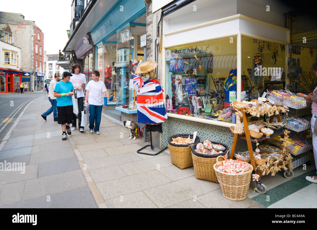 Un gruppo di adolescenti villeggiante oltrepassando dono e negozi di souvenir nella cittadina balneare di Swanage, Dorset. Regno Unito. Foto Stock