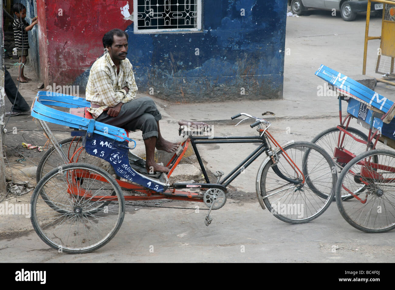 Un ciclo di risciò operatore sulle strade di New Delhi Foto Stock