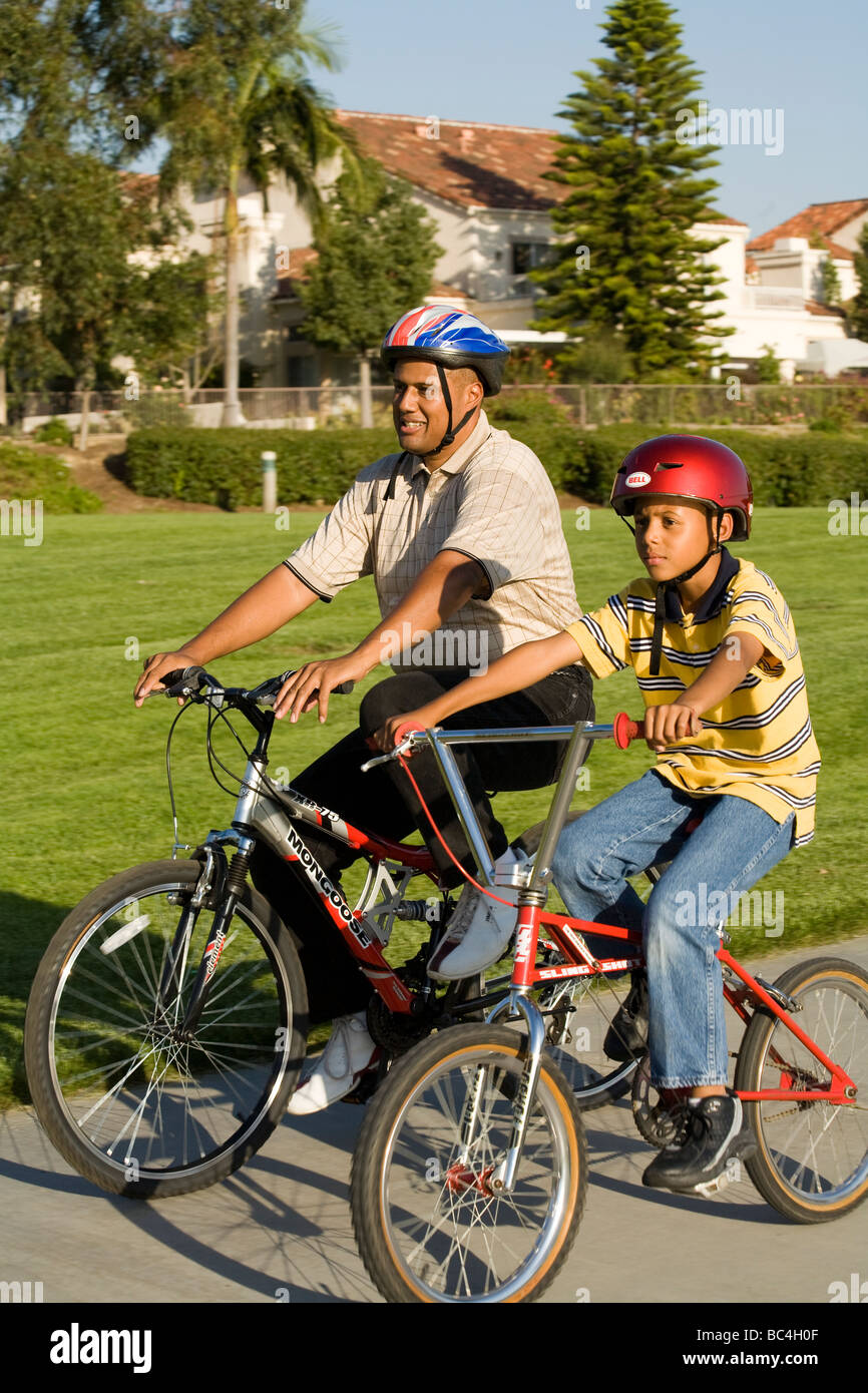 Padre papà bambino equitazione biciclette insieme correre in bici Bicicletta 8-9 anno anni appartenenti a una minoranza etnica California afro-americano di padre negli Stati Uniti Foto Stock