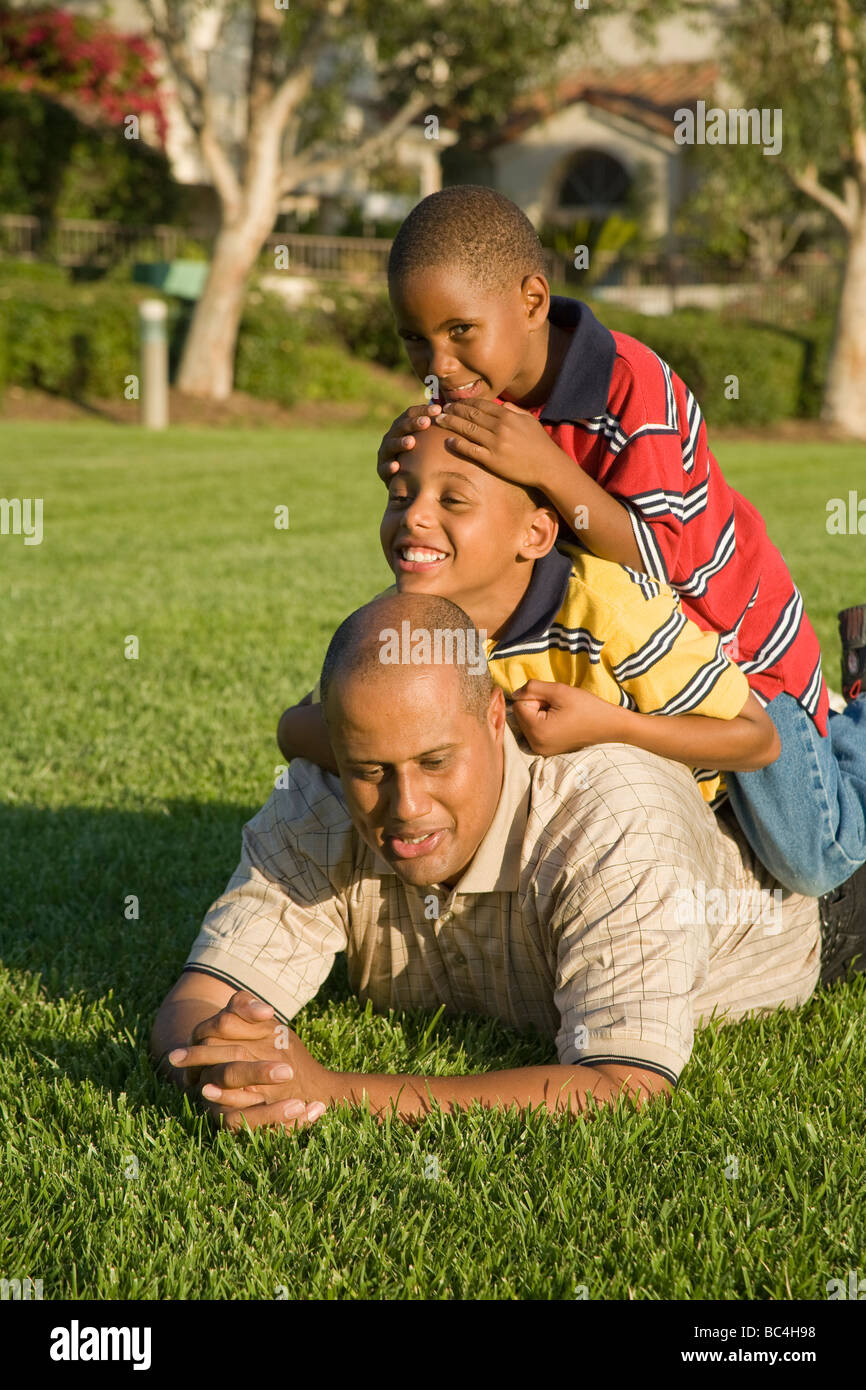 California papà ragazzo afro-americano di padre e due ragazzi godere salendo su ogni altro all'esterno. Signor © Myrleen Pearson Foto Stock