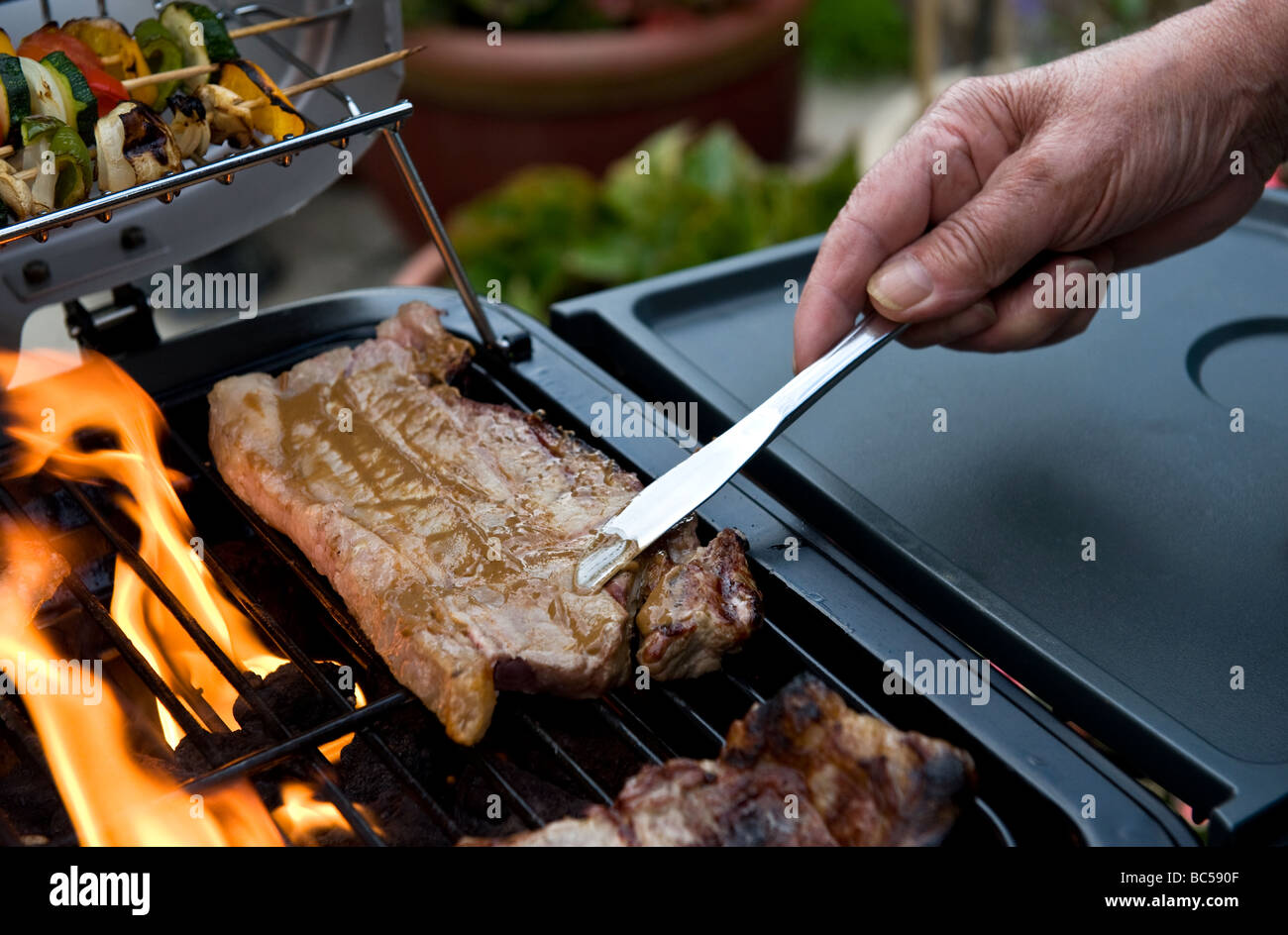 Uomo di senape spandimento su una bistecca di controfiletto su un barbecue Foto Stock