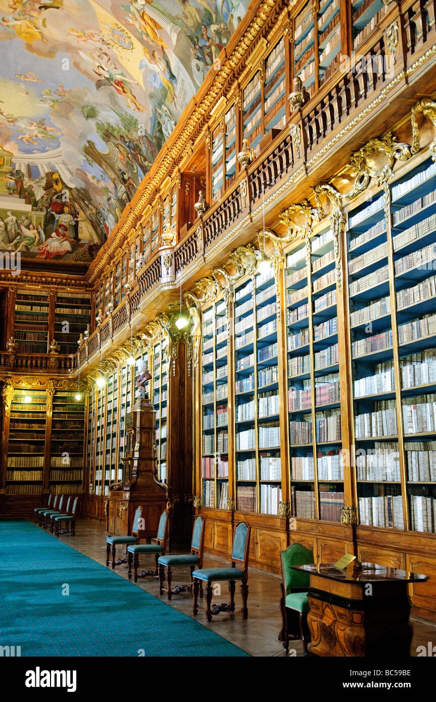 PRAGA, Repubblica Ceca: L'interno mozzafiato della Biblioteca Strahov, situata all'interno del Monastero di Strahov a Praga. Questa immagine cattura l'opulento design barocco della biblioteca, probabilmente concentrandosi sulla sala filosofica. La sala presenta scaffali in noce da pavimento a soffitto pieni di antichi tomi, uno splendido soffitto affrescato raffigurante scene allegoriche di conoscenza umana e intricati dettagli architettonici che mettono in mostra il massimo dell'artigianato e della visione artistica del XVIII secolo. Foto Stock