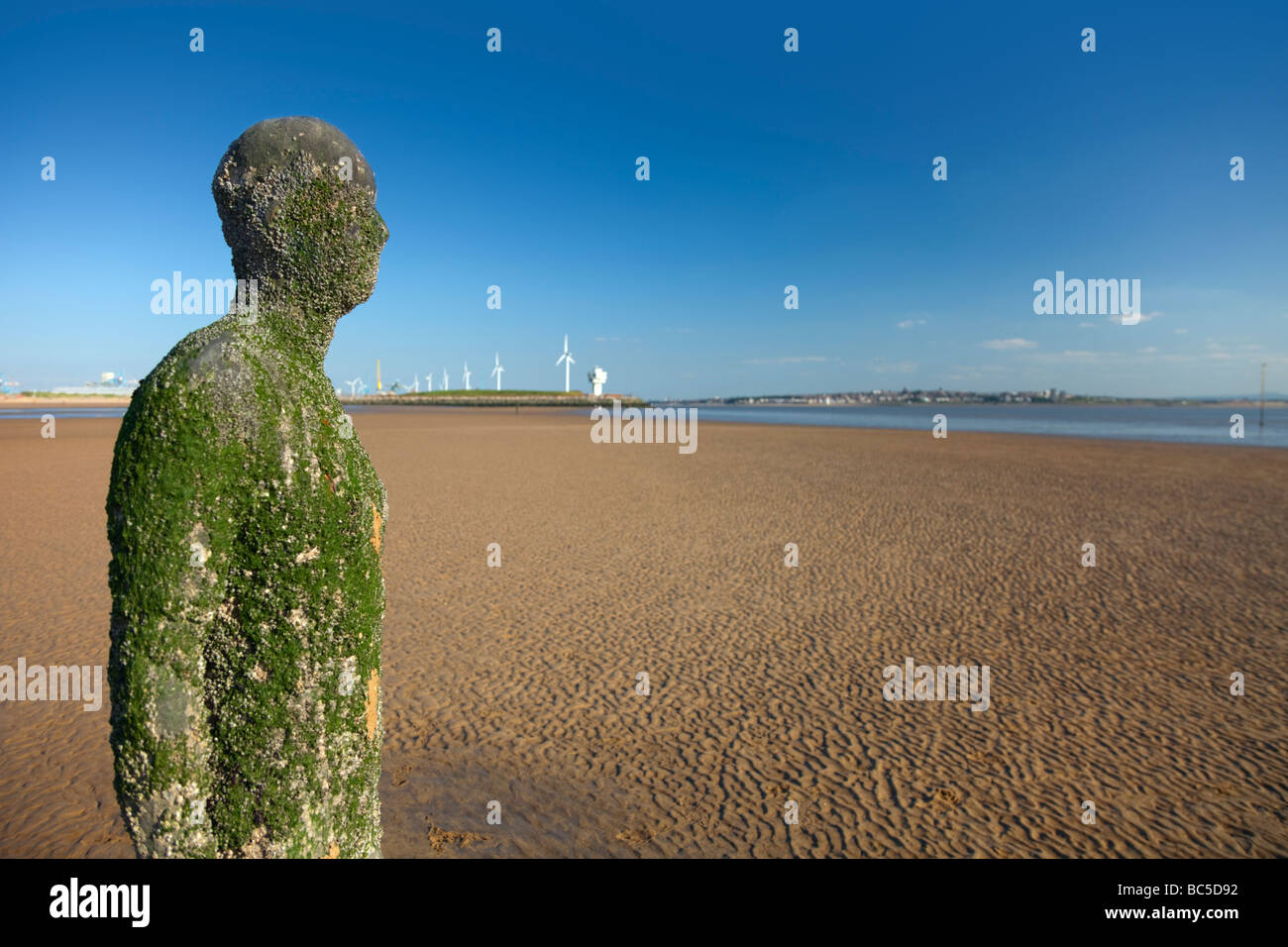 Sir Antony Gormley artwork in altro luogo si trova sulla spiaggia di Crosby che forma parte della costa di Sefton, entro il Liverpool City regione del Regno Unito. Foto Stock