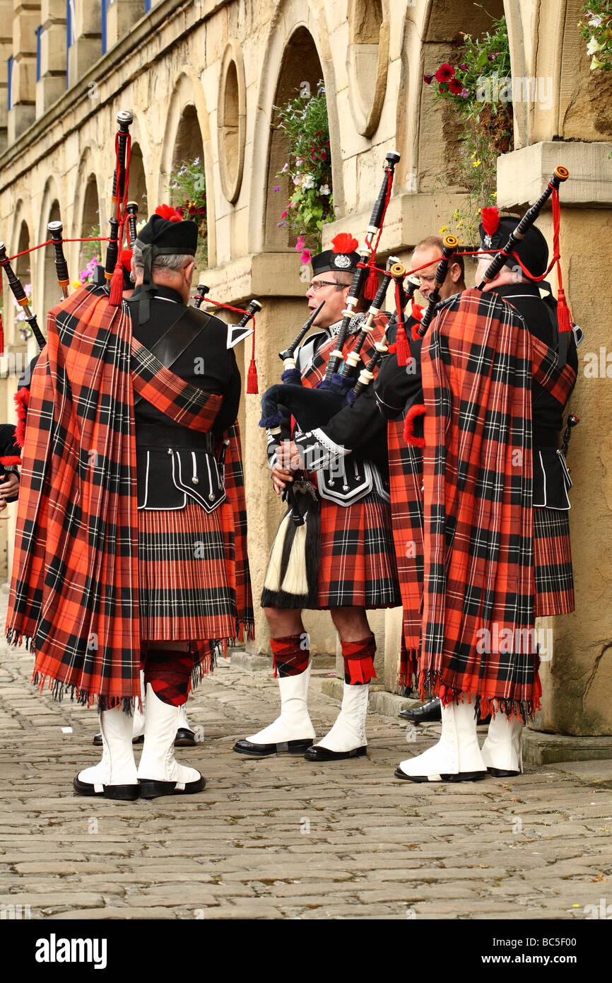 Piper ornato nel Ramsay Tartan giocando le cornamuse tubi e sono un tradizionale strumento scozzese utilizzato in Marching Band Foto Stock