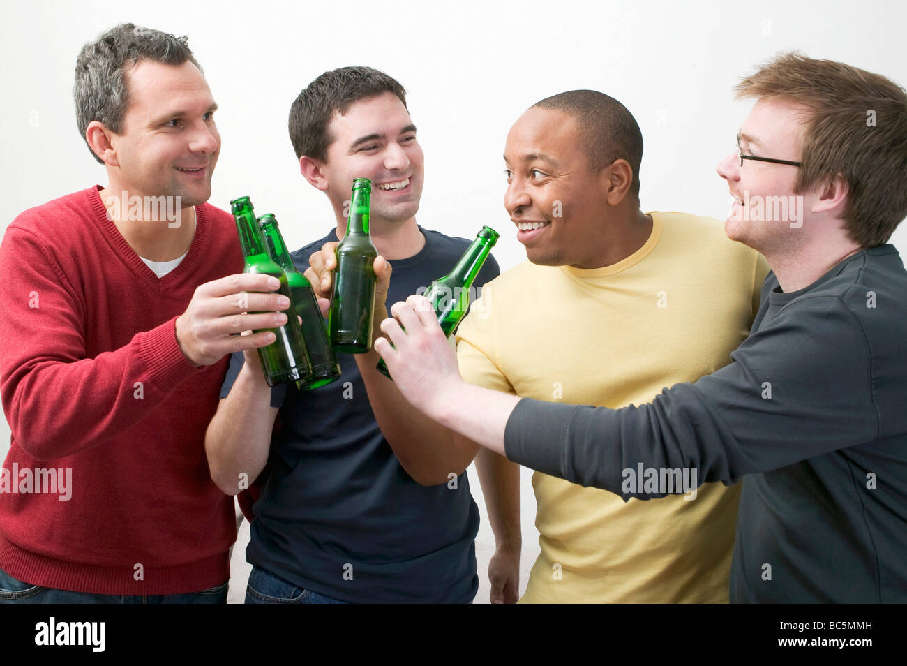 Quattro uomini tintinnio di bottiglie di birra - Foto Stock