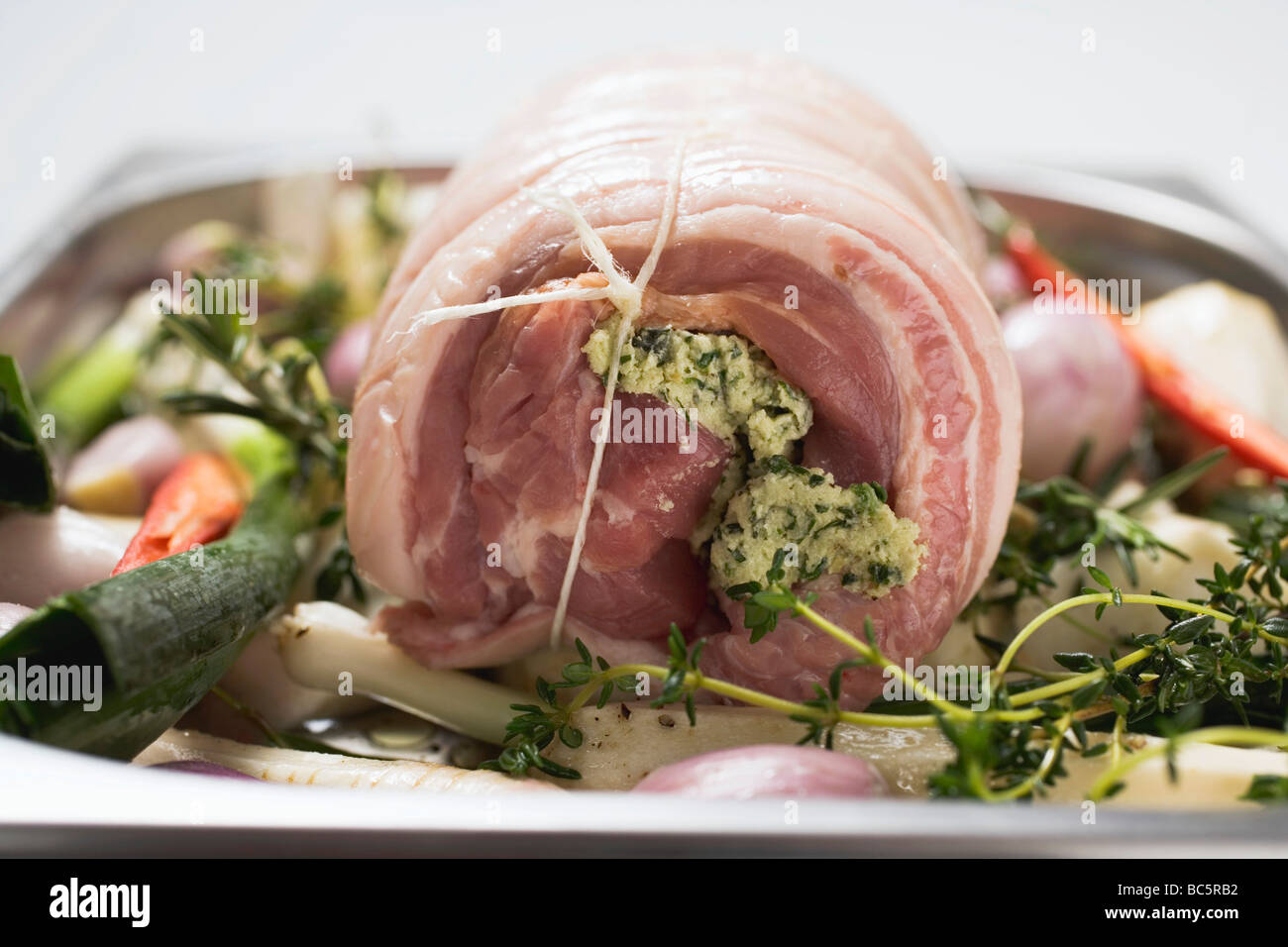 Laminati di arrosto di maiale con ripieno di erbe su letto di verdure - Foto Stock
