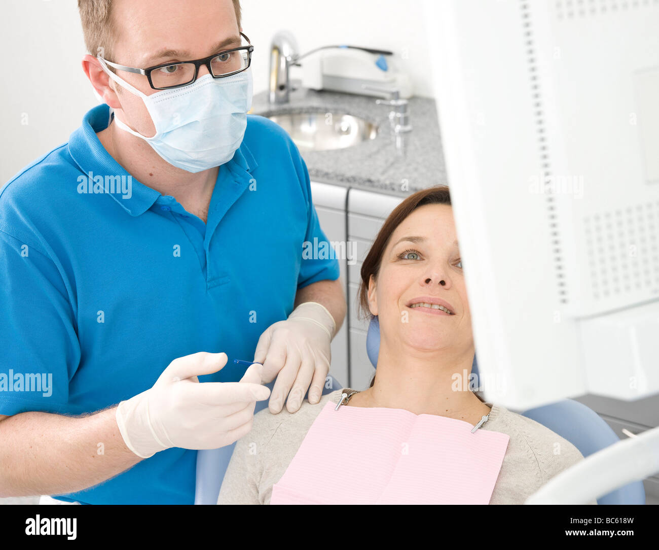 Maschio di dentista e paziente guardando il monitor Foto Stock