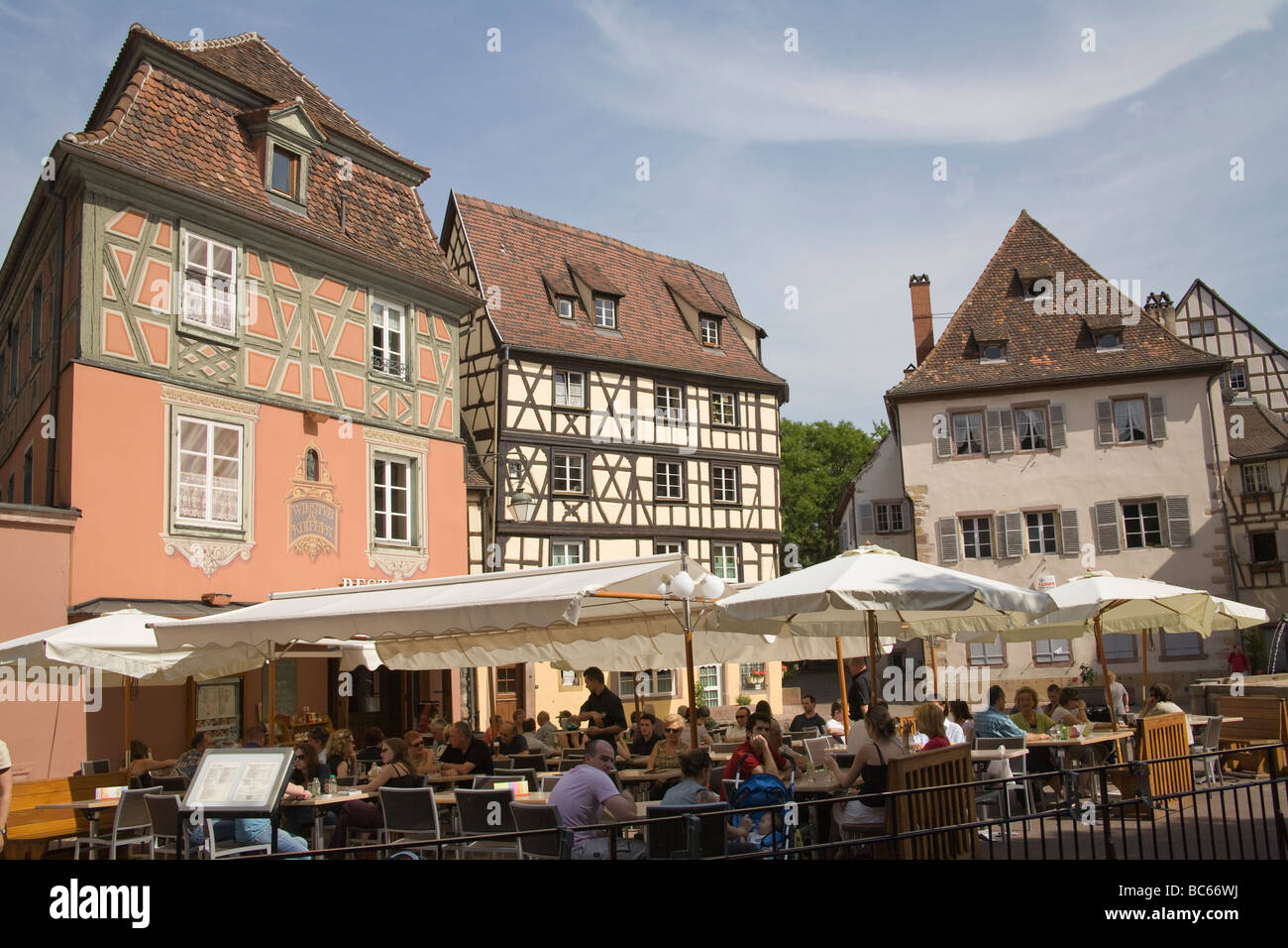 Colmar Alsace Francia UE ai visitatori per cenare fuori nel sole di primavera in un ristorante a Place de L Ancienne Douane Foto Stock