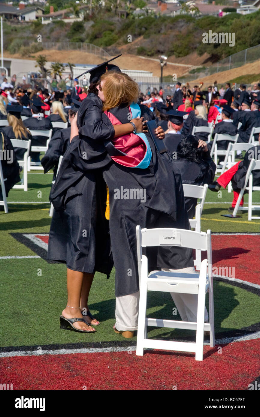 Un felice high school girl senior avvolge il suo insegnante preferito a graduazione in San Clemente CA Foto Stock