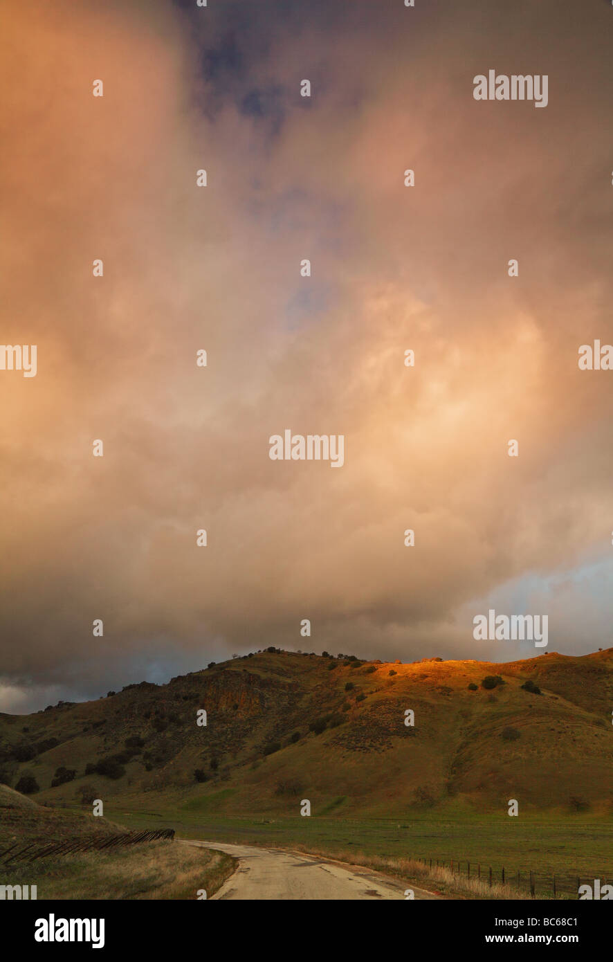 Arancione drammatico nuvole sulla strada rurale Foto Stock