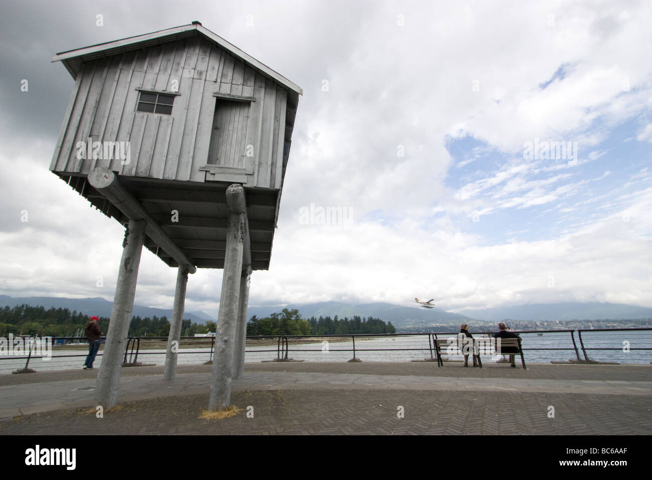 Vancouver Canada persone sedute sulla panchina a guardare gli aerei stol che atterrano a Coal Harbour Foto Stock