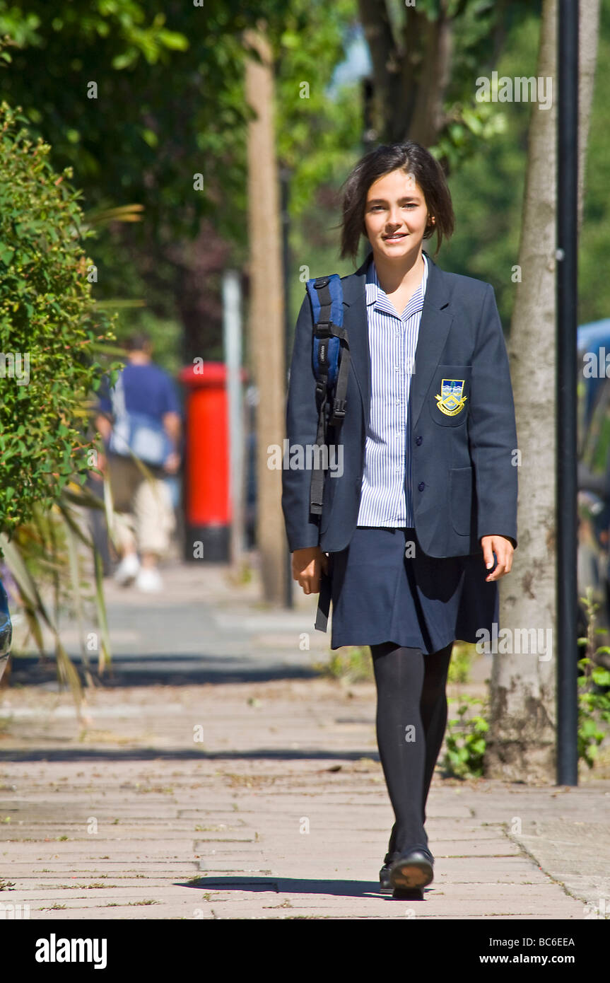 Una giovane ragazza caucasica (12) sorridere mentre passeggiate home/a scuola indossando la sua uniforme. Foto Stock