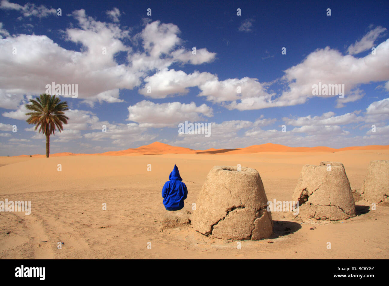 Persona che indossa Marocchino tradizionale djellabah dai forni di fango cercando di Erg Chebbi dune di sabbia del deserto del Sahara, Merzouga, Moroccco Foto Stock