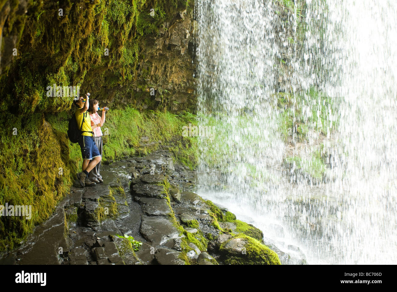 Walkers prendere una pausa dietro una cascata. Foto Stock