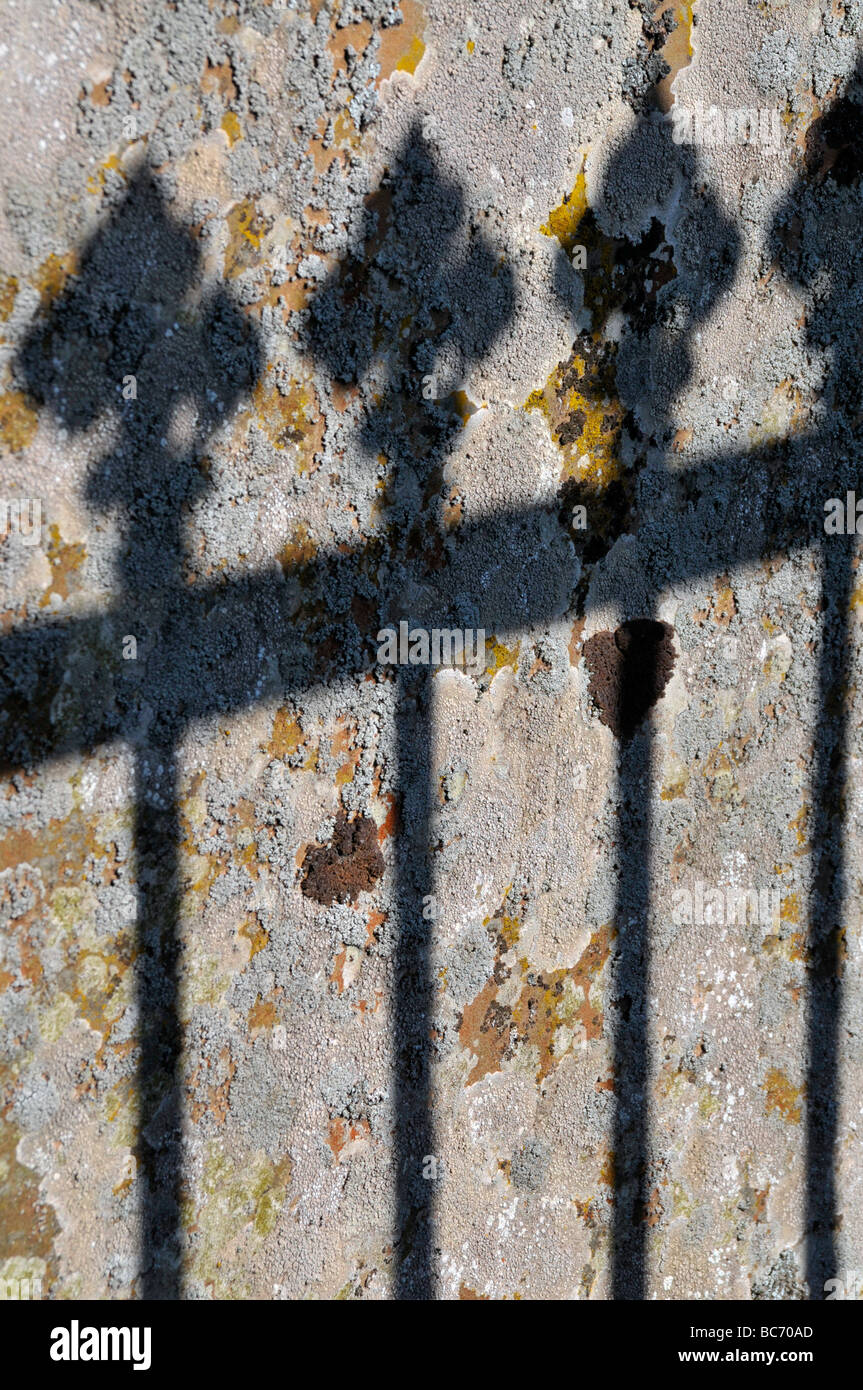 Dettaglio di un'ombra su un muro di pietra di un cancello aperto. Foto Stock