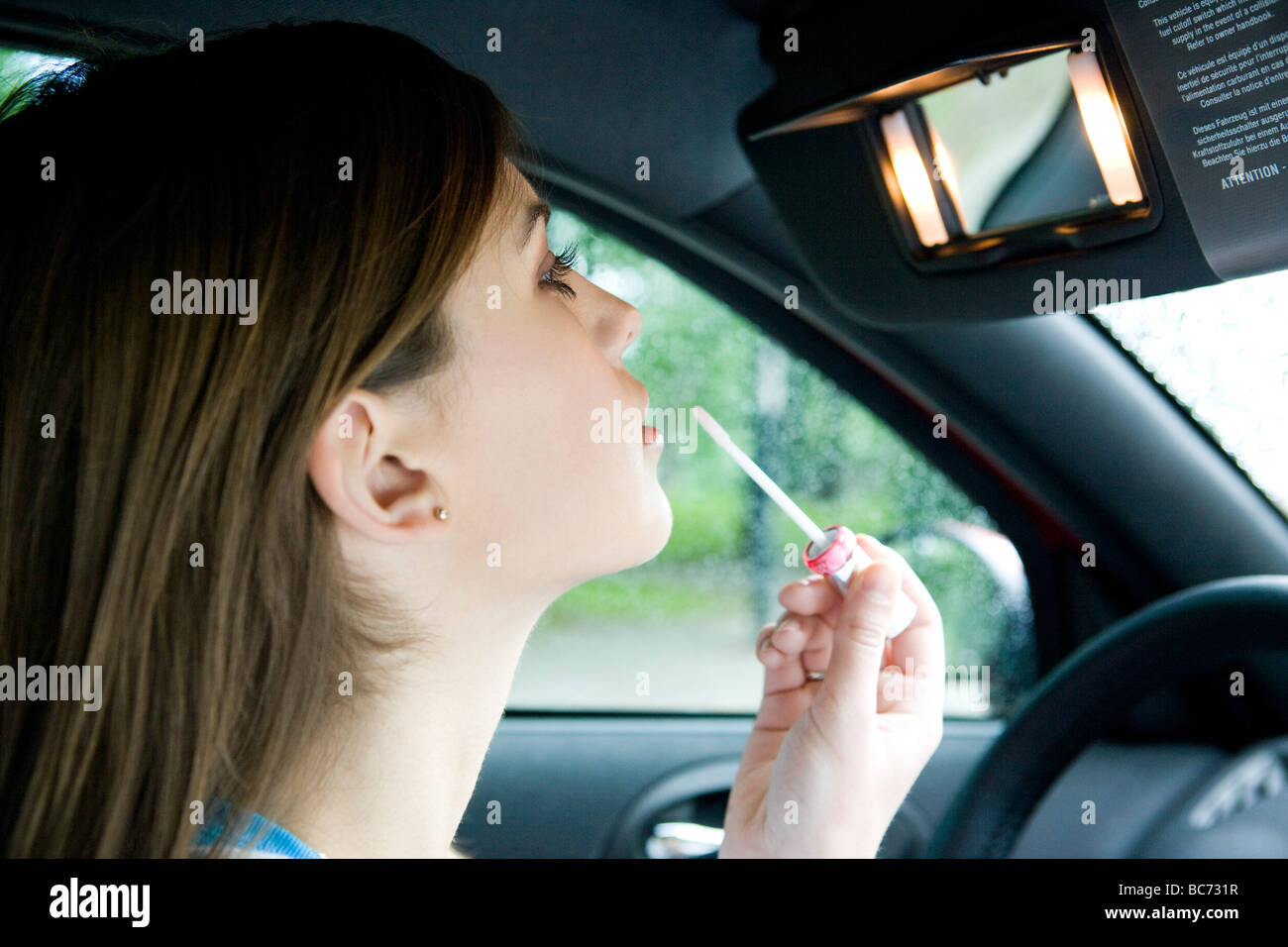 Donna rossetto utilizzando specchio auto Foto Stock