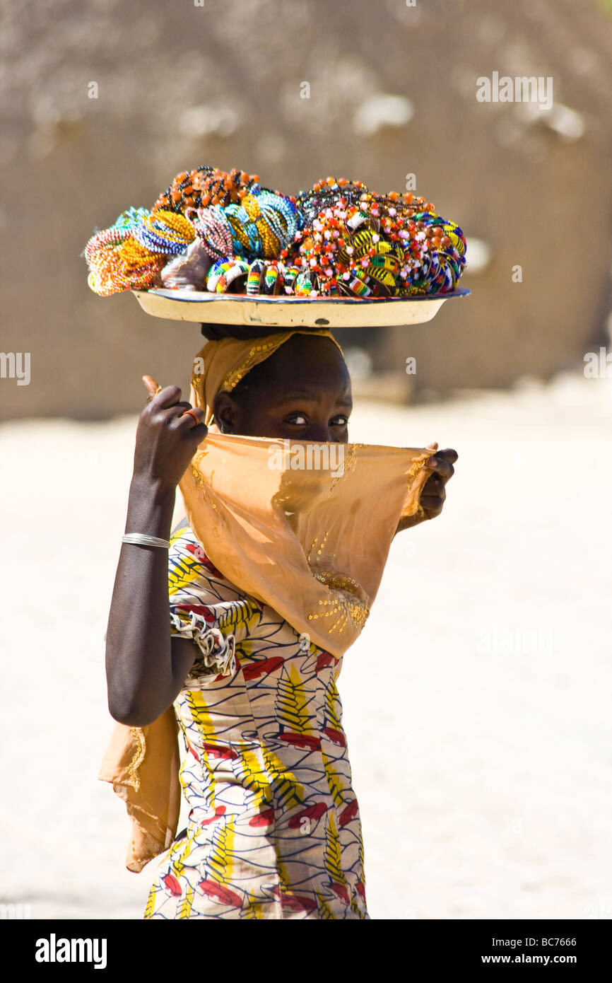 Donna con negozio di souvenir equilibrato sul suo capo in Timbuktu Mali Foto Stock