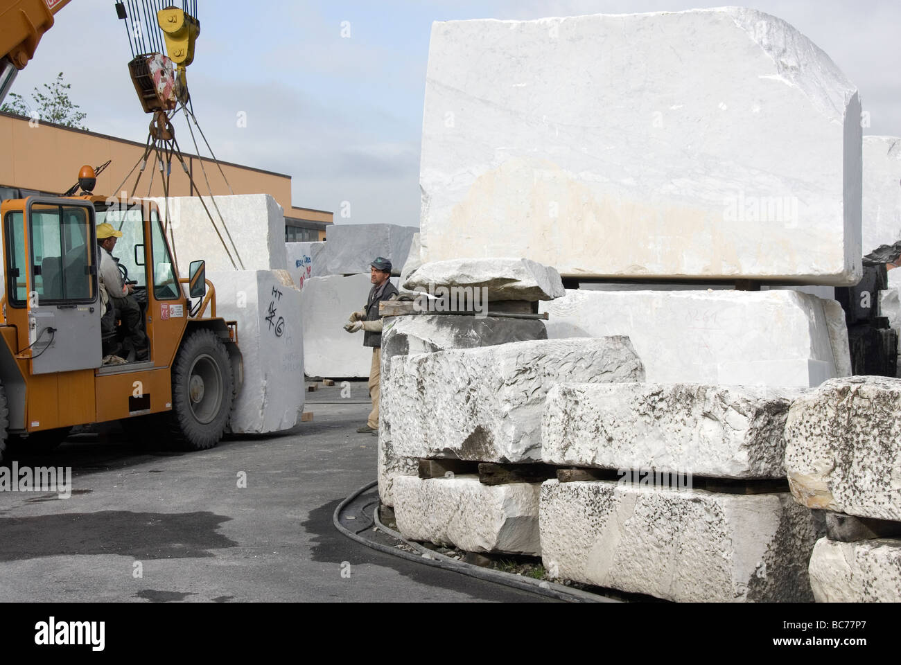 Gru mobile in movimento blocchi gigante di puro marmo bianco di Carrara nel cantiere di contenimento delle Cave Michelangelo Foto Stock