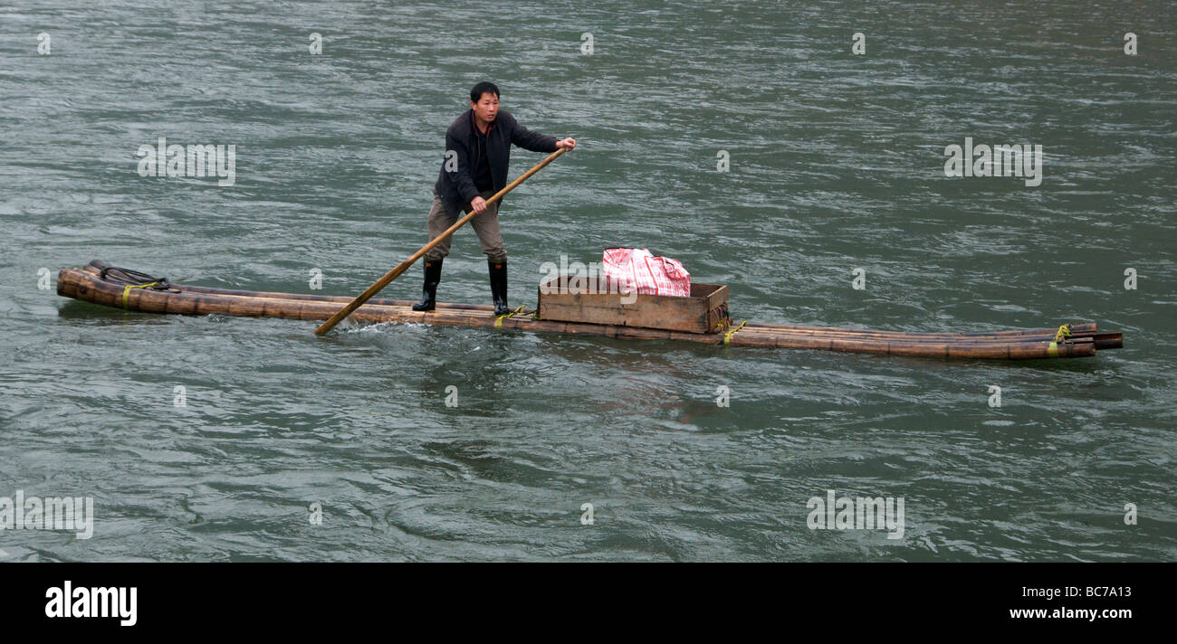 Fisherman canottaggio zattera di bambù in acqua turbolenta Fiume Li Guanxi Cina Foto Stock