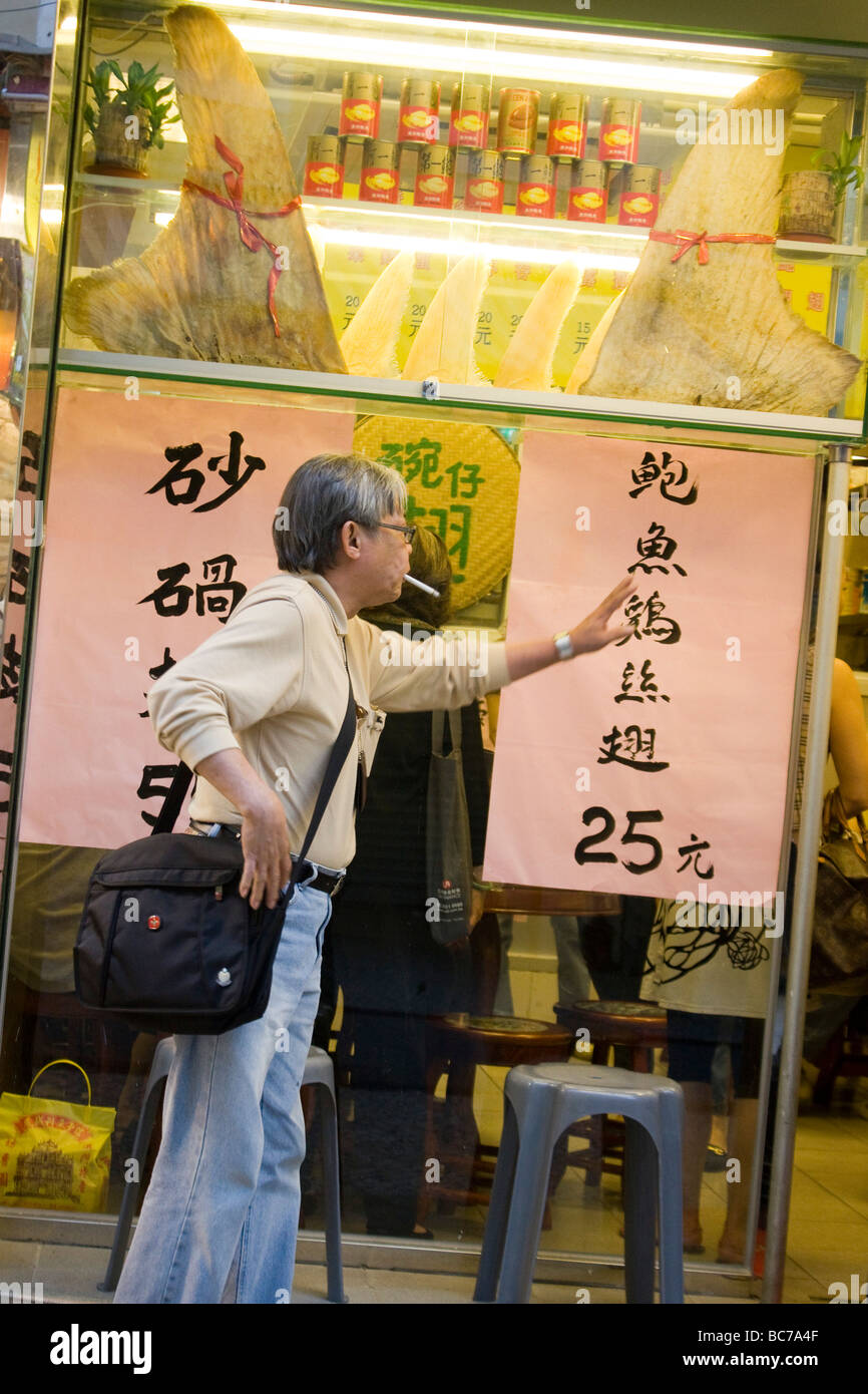 Uomo che guarda a pinna di squalo in negozio cinese a Macao Foto Stock