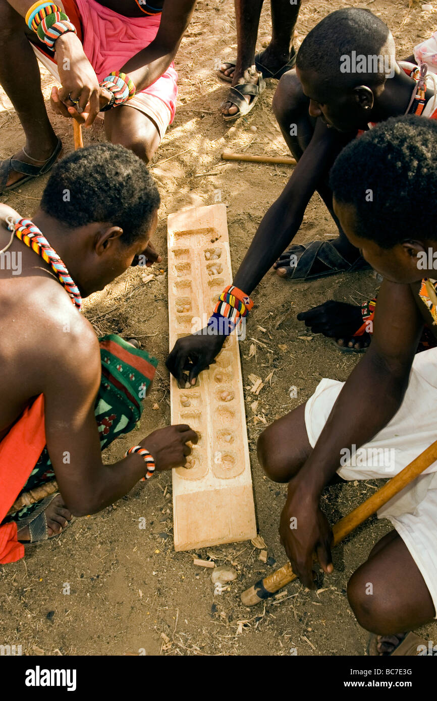Samburu uomini la riproduzione di gioco della famiglia dei mancala - Samburu riserva nazionale, Kenya Foto Stock
